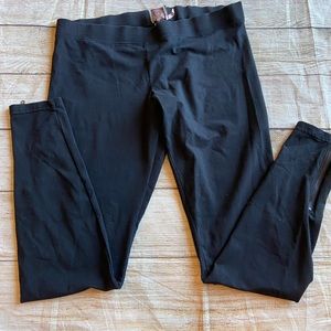Women’s black leggings with zippers at the ankles.